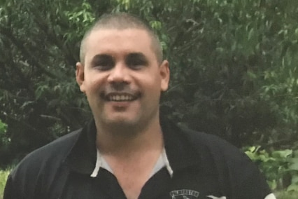 A picture of missing man Richard Roe, smiling and wearing a black rugby jersey.