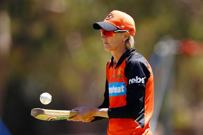 Lisa Keightley bounces a cricket ball on a bat.