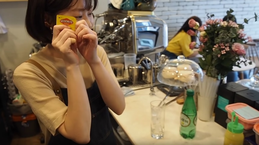 A Korean staff member at the Old Cap cafe in Seoul holds a small container of Vegemite spread to her ear.