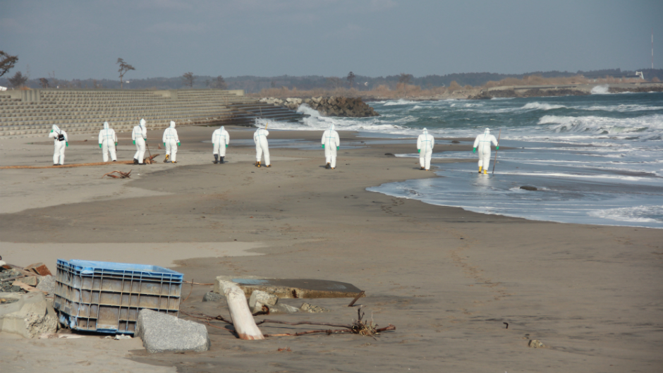 Police in white suits searching the beach