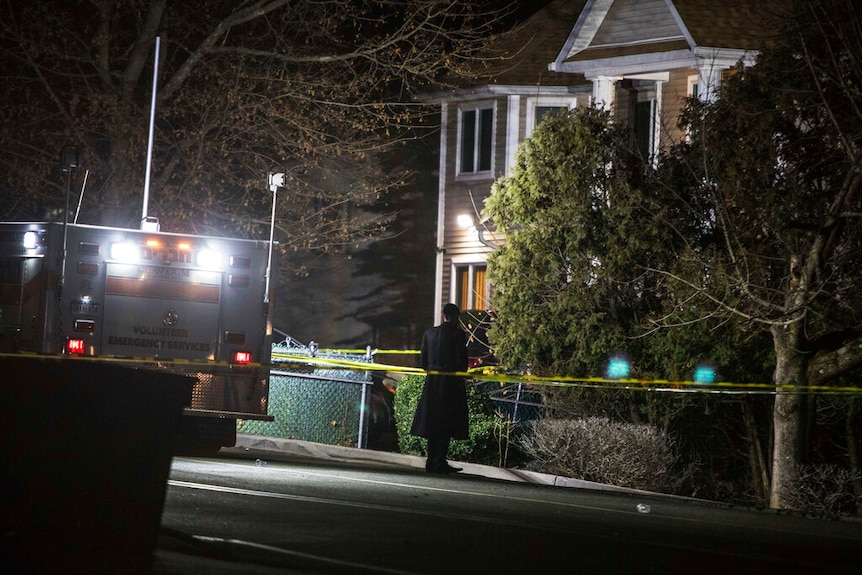 At night, you view a lone Orthodox Jewish man behind police tape between a Jewish ambulance and a house.