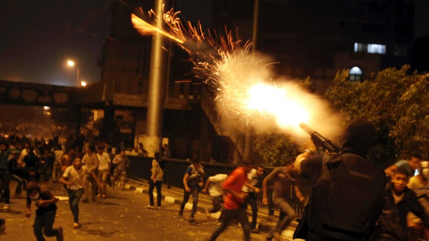 A riot police officer fires tear gas during clashes between pro and anti-Mohammed Morsi protesters in Cairo.
