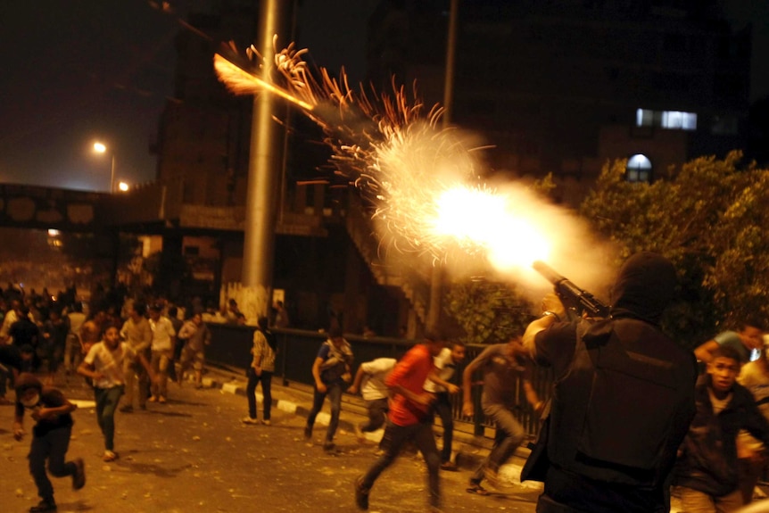 A riot police officer fires tear gas during clashes between pro and anti-Mohammed Morsi protesters in Cairo.