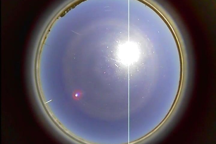 A small bright dot in the sky next to the sun, captured be a resident's sky cam.