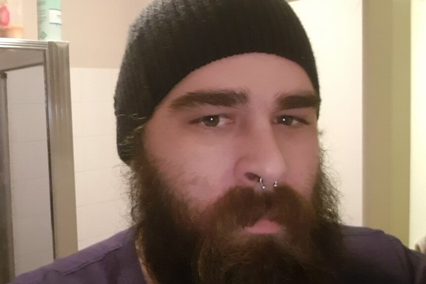 A man in a beanie with a beard and nose piercing.