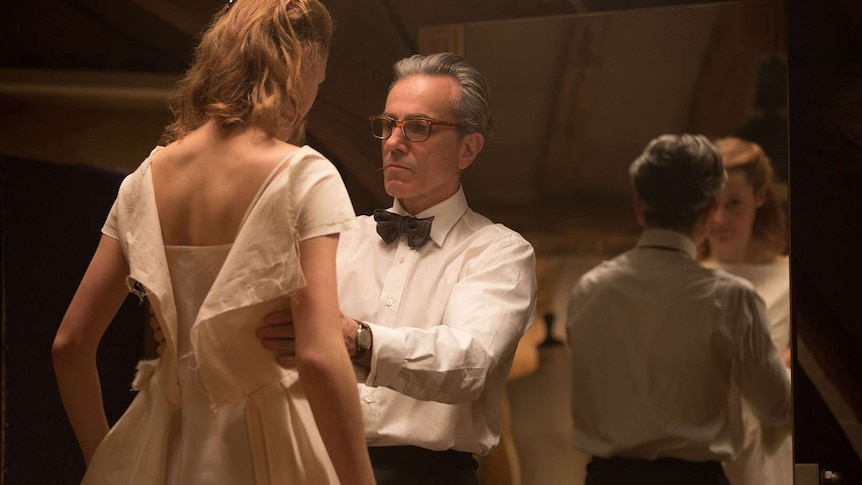 Daniel Day-Lewis as Reynolds Woodcock, working as a dressmaker and making measurements on a dress worn by a young woman.