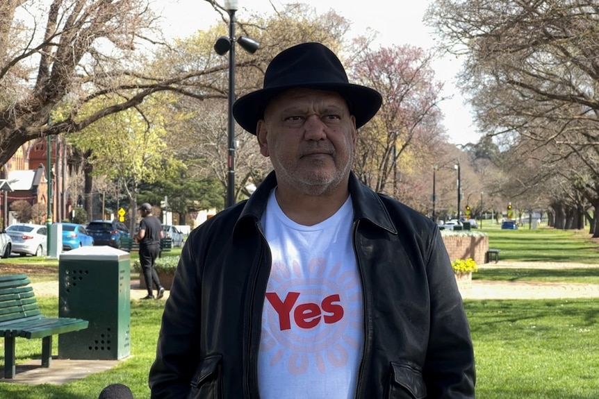Noel Pearson standing in a park wearing 'Yes' T-shirt