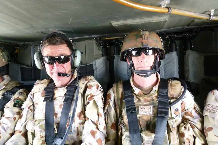 Angust Houston and Angust Campbell sit side by side in uniform in a helicopter