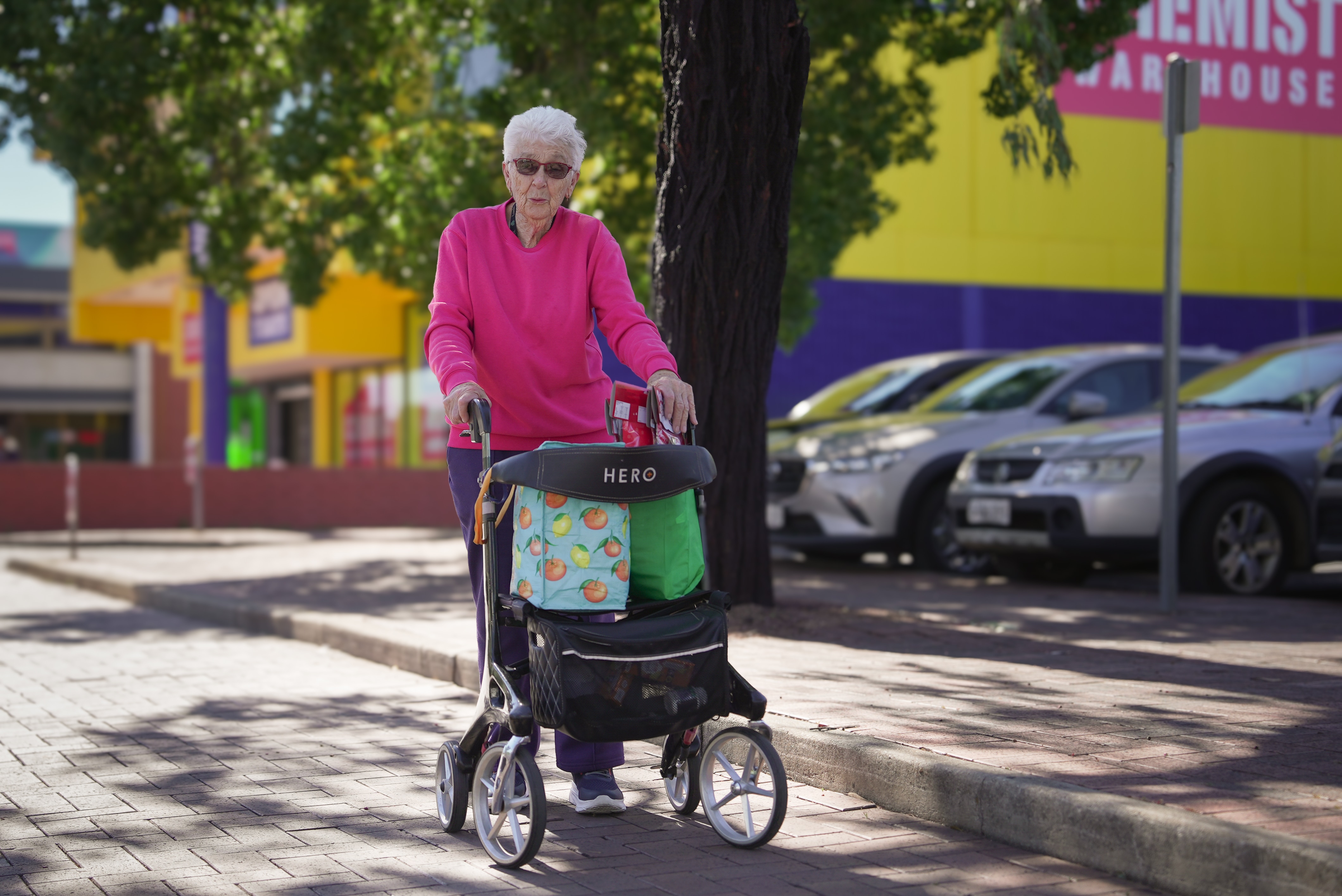 An elderly woman with her walker smiles at the camera.