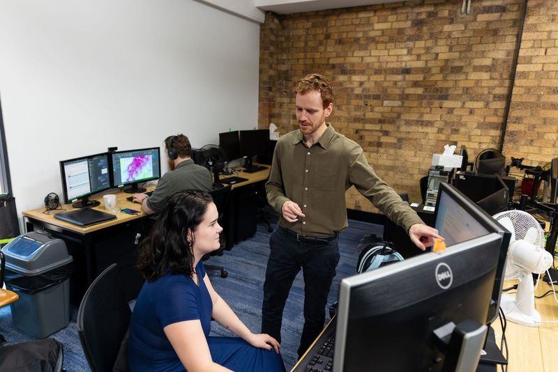 A man standing and talking to a female at the computer 