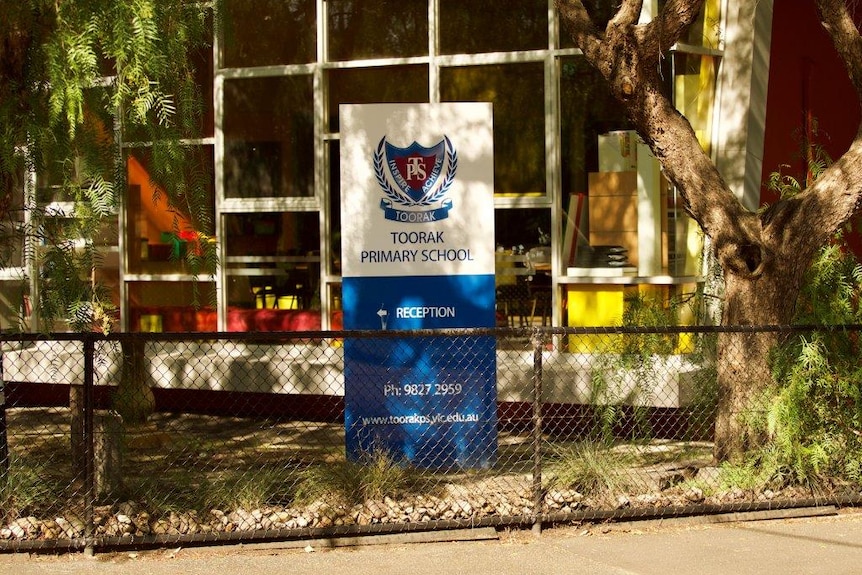 A Toorak Primary School sign behind a waist-high chain link fence at the school.
