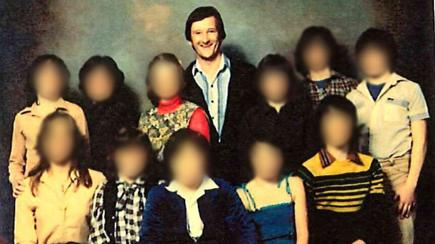 An archive shot of a man surrounded by children whose faces are blurred.
