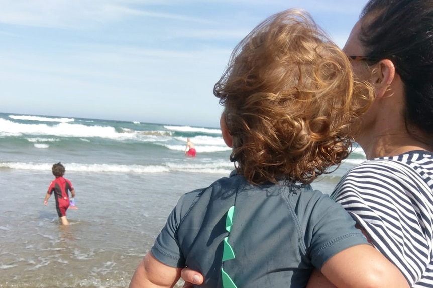 Josie Sargent carries her son at the beach