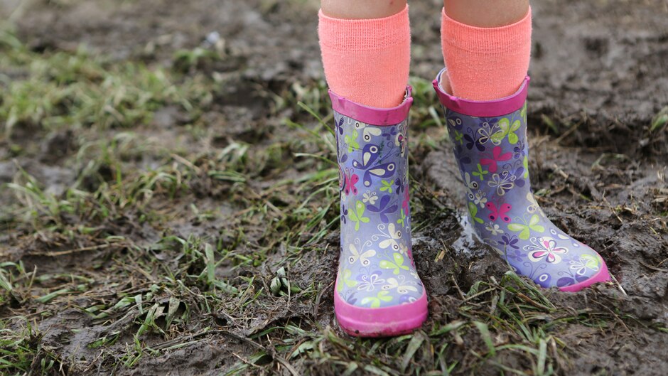 Purple gumboots with a butterfly pattern in the mud.