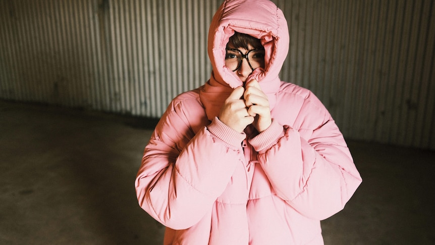 woman wearing a pink puffer jacket and peaking through the hood