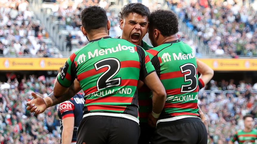Three South Sydney NRL players embrace as they celebrate a try.