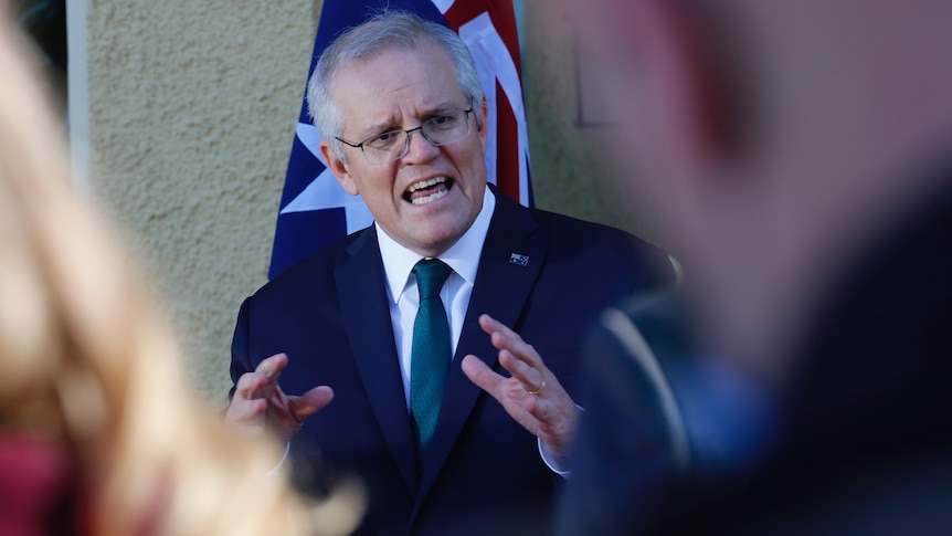 The Prime Minister gestures as he explains something to an unidentifiable journalist.