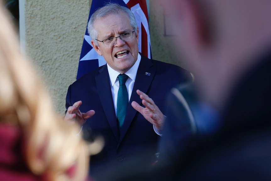 The Prime Minister gestures as he explains something to an unidentifiable journalist.