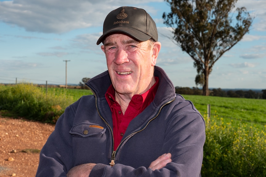 Graeme 'George' Somers standing on his mixed-farming property with a paddock and tree in the background.