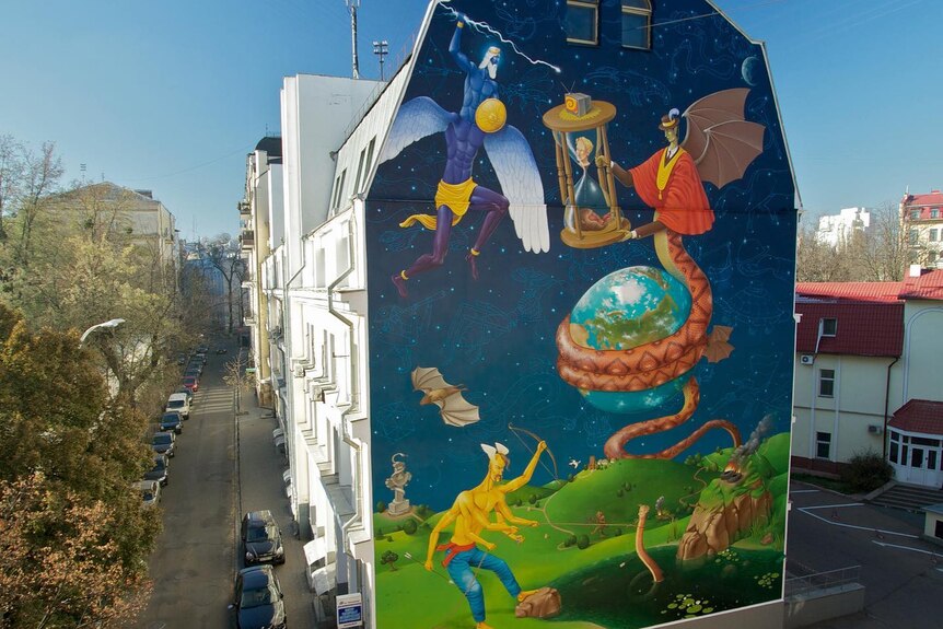 a bright large scale mural is painted on the side of a building in a Kyiv street.