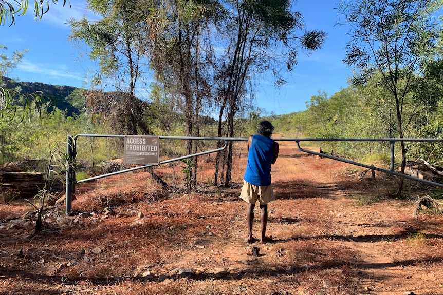 Jeffrey Lee stands at a gate on a dirt road in Kakadu.