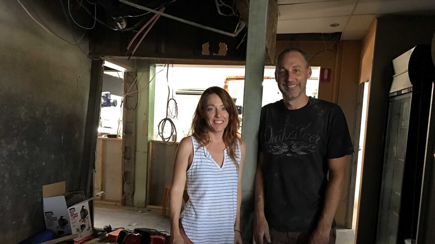 Two people stand in a room under construction