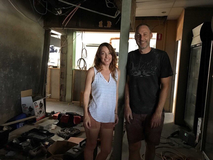 Two people stand in a room under construction