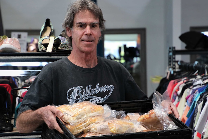 Stephen Reynolds holds a large tray of bread rolls.