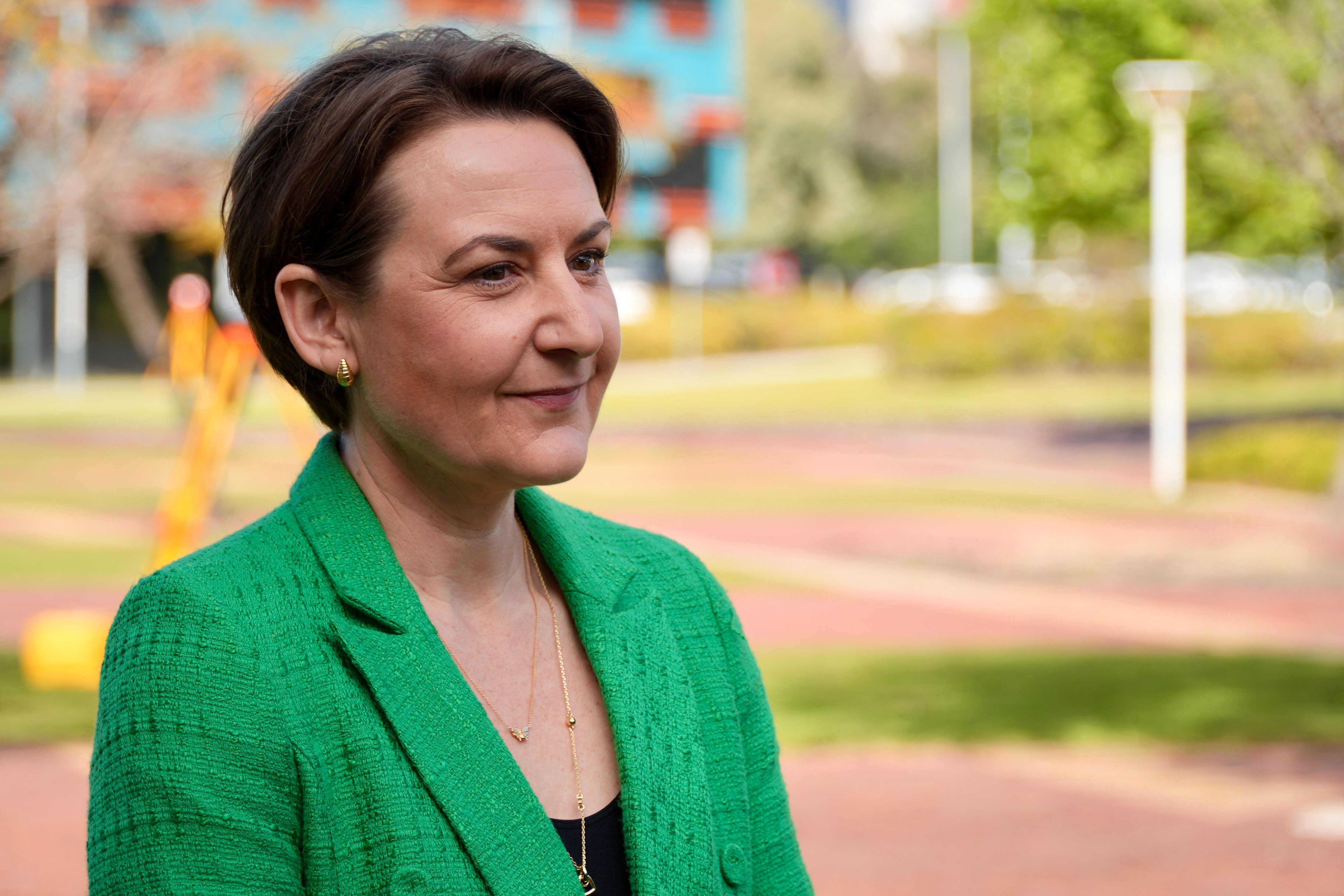 Amber-Jade Sanderson viste una chaqueta de traje verde y sonríe.