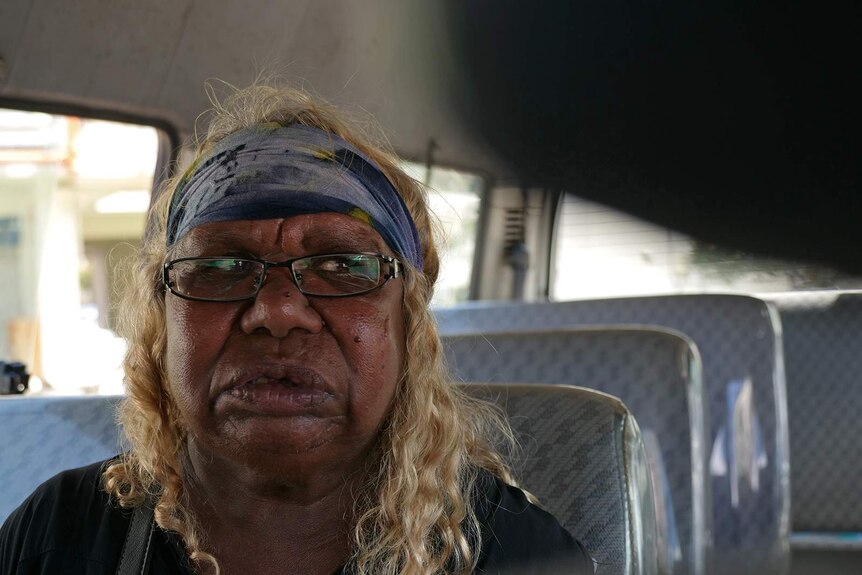 A close-up photo of an Indigenous woman in the back seat of a van.
