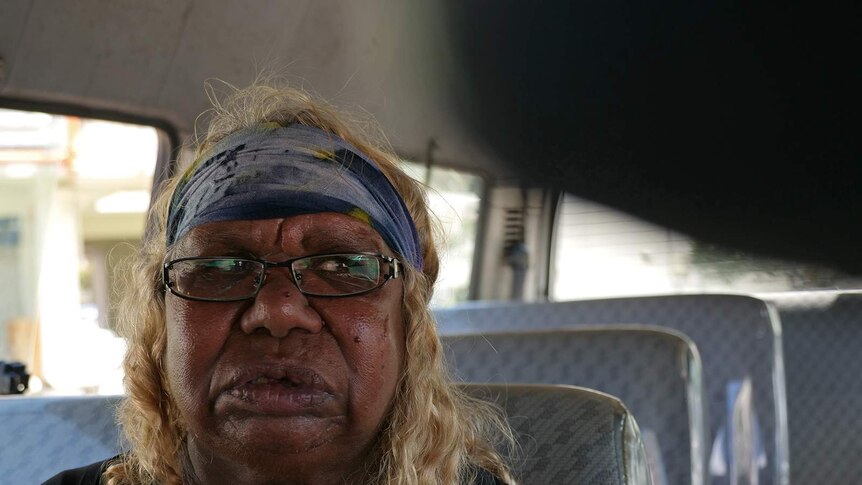 A close-up photo of an Indigenous woman in the back seat of a van.