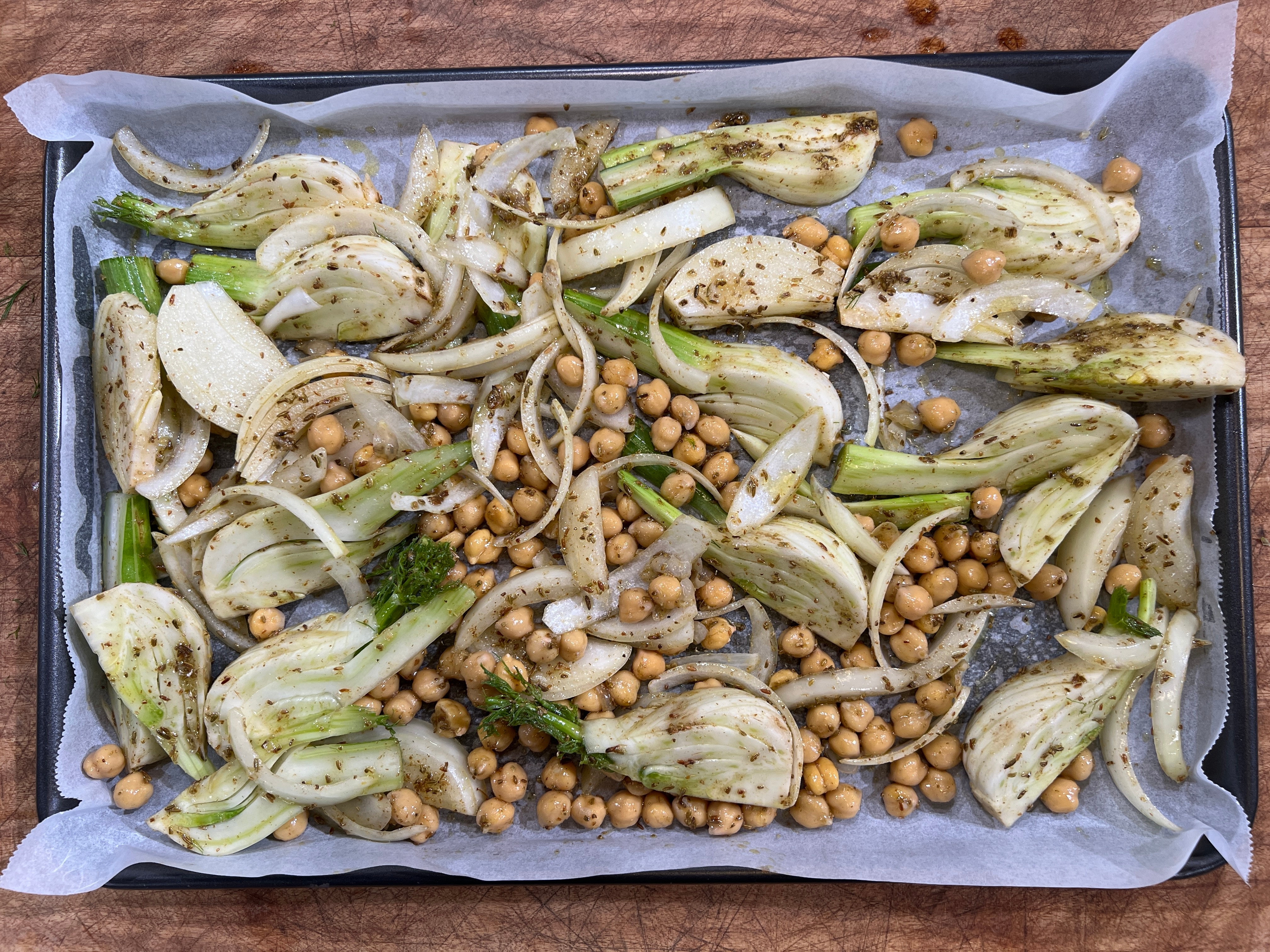 A picture of fennel and chickpeas on a lined baking tray.