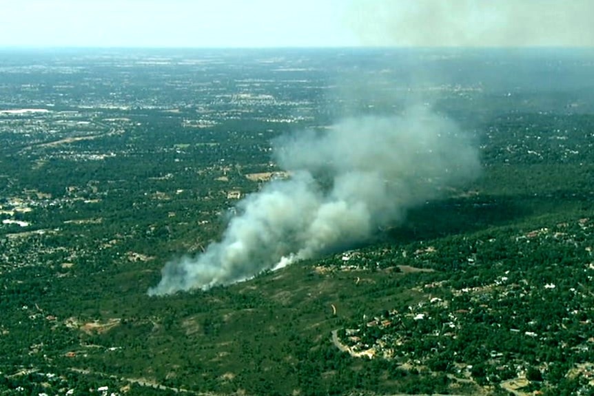 An aerial shot of fire burning and blowing smoke over homes