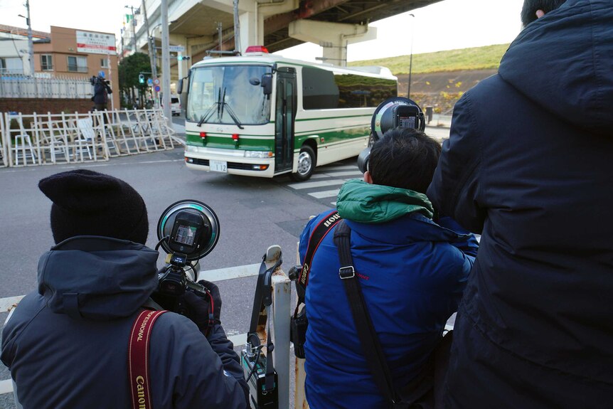 Photographers film a vehicle presumably carrying former Nissan chairman Carlos Ghosn to Tokyo Detention Centre.
