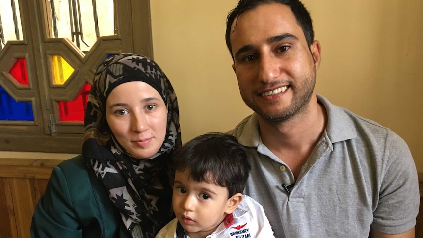 Tuqa and Derar sit with their small son Hamza on their laps.