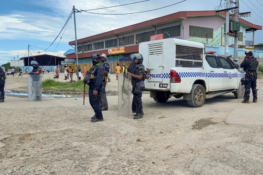 Solomon Islands police officers stand with a truck at a checkpoint in Honiara
