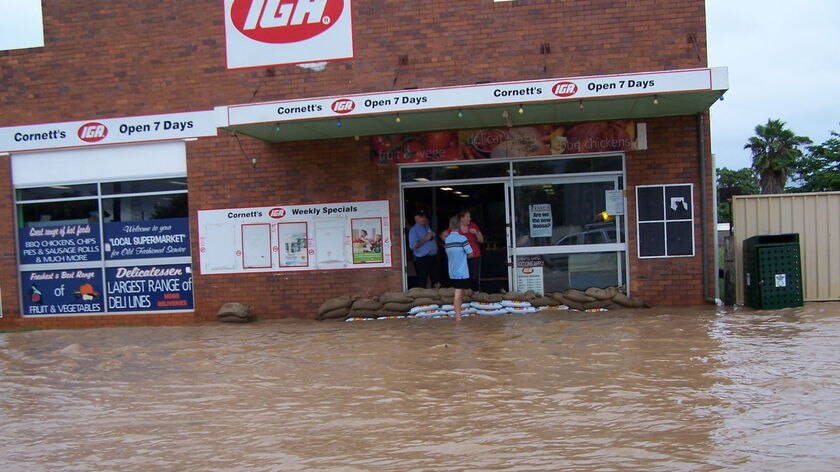 Owners at Charleville sandbag their store against rising floodwaters.