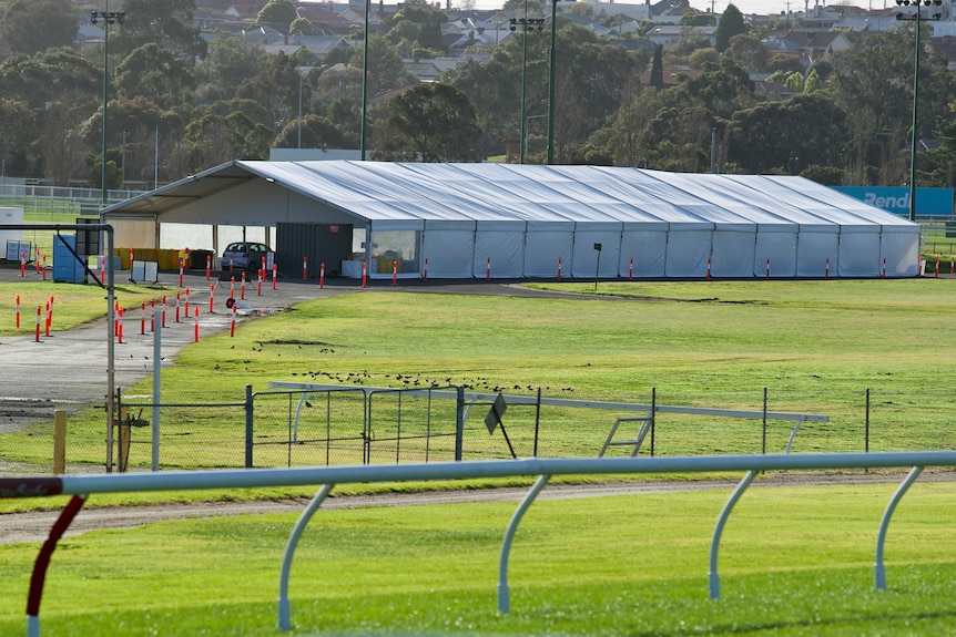 The racetrack and central oval at Moonee Valley Racecourse, where a large pavilion lies empty with orange traffic markers.