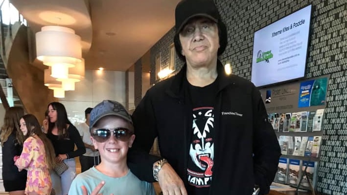 Small boy posing with man in a black KISS t-shirt and black shirt