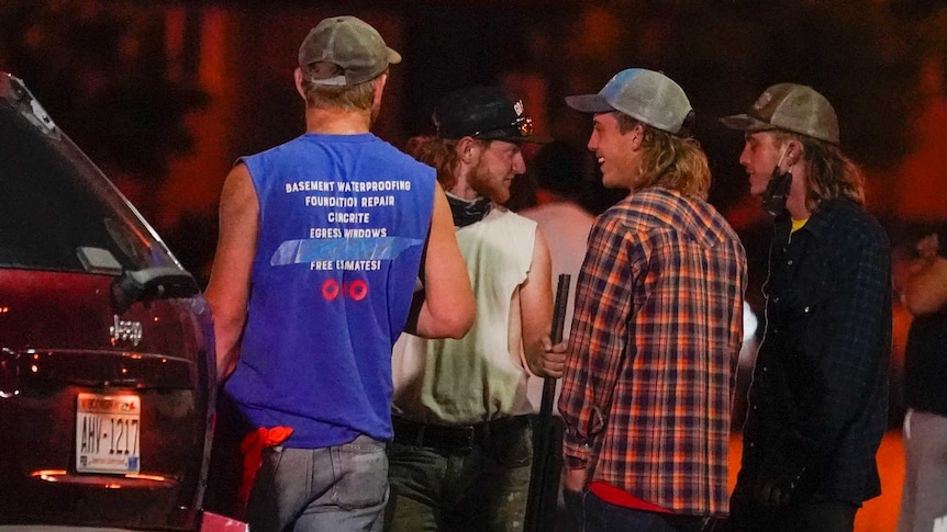 Four men stand near a car holding guns during protests in Kenosha.