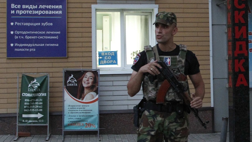 An armed serviceman stands guard at a cordon.