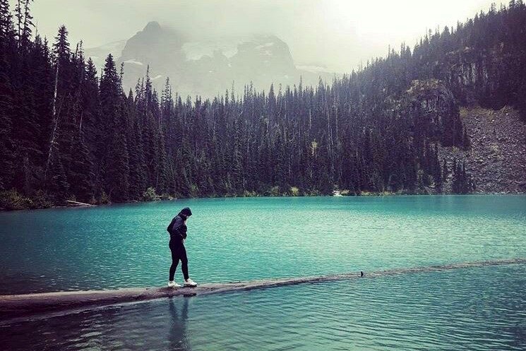 A woman walking along a partly submerged walkway into a blue lake.