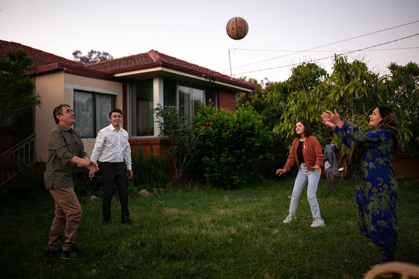 Two men and two woman play with a ball.