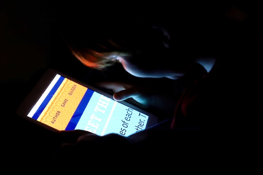 A child's face is illuminated by a tablet.