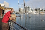 A man leans over a railing looking at a sunken ship in Ross Creek