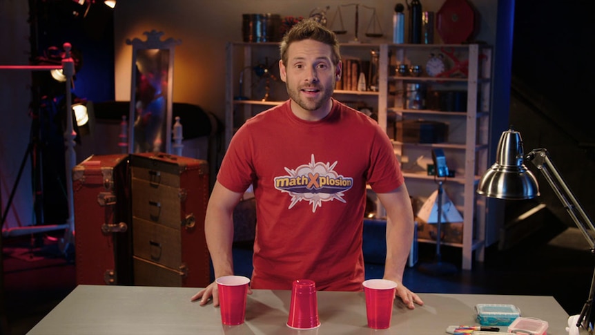 Man stands in front of 3 cups on table