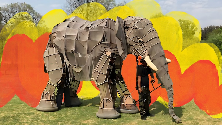An elephant puppet being operated by two people.
