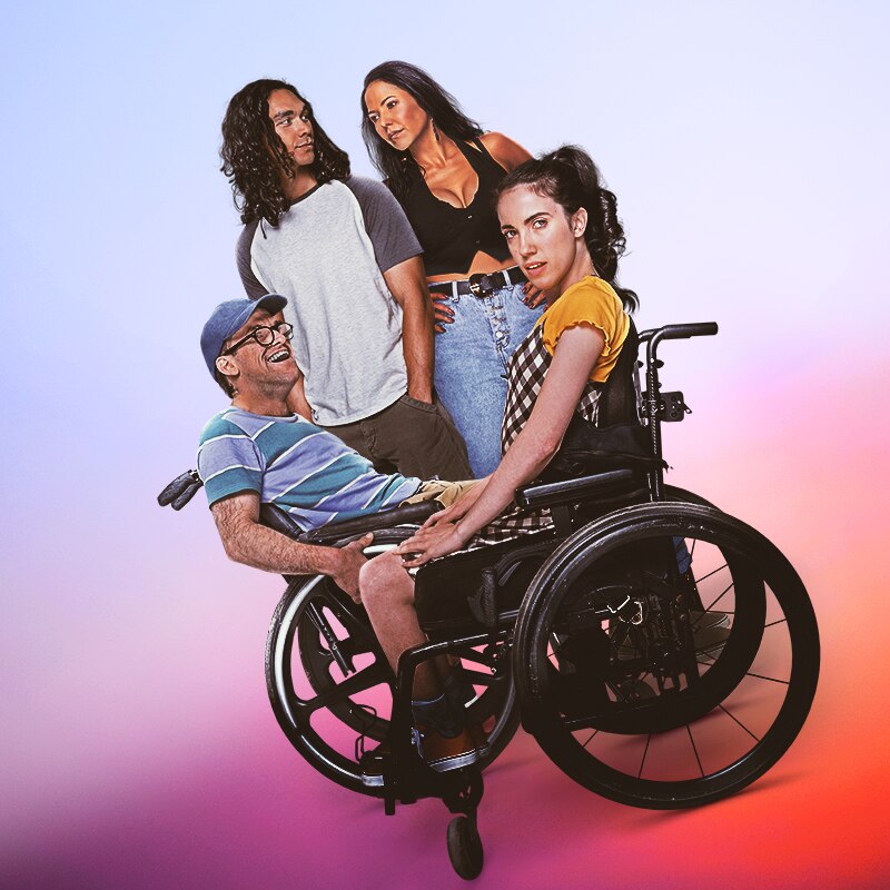 A man wearing a cap and a woman in a yellow tshirt are in a wheelchair as another man and a woman stand in the background