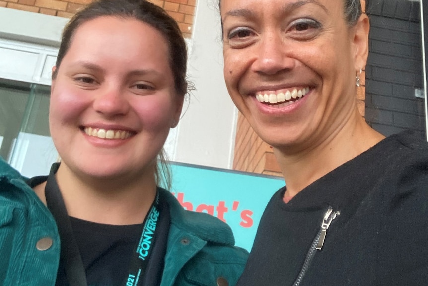 Two women stand next to each other and smile at the camera