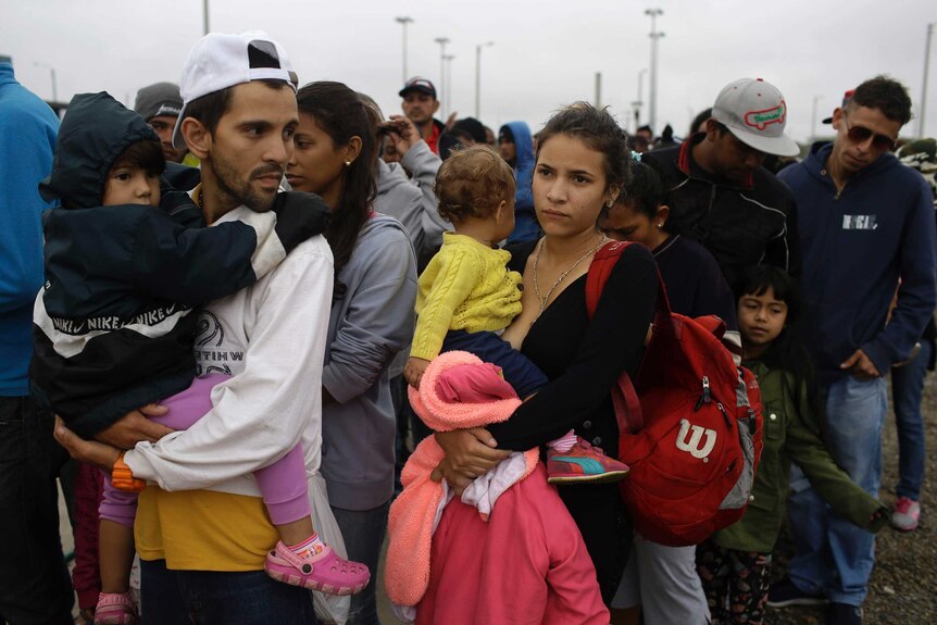 Venezuelan families wait for breakfast after crossing border into Peru.